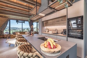Eine moderne Küche mit einer großen Kochinsel, Holzschränken und Blick ins Freie.