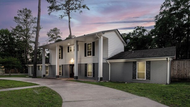 A two-story residential building with a covered porch, a driveway, and a view of the surrounding trees. - Empress Sunlit Villa (Cypress)