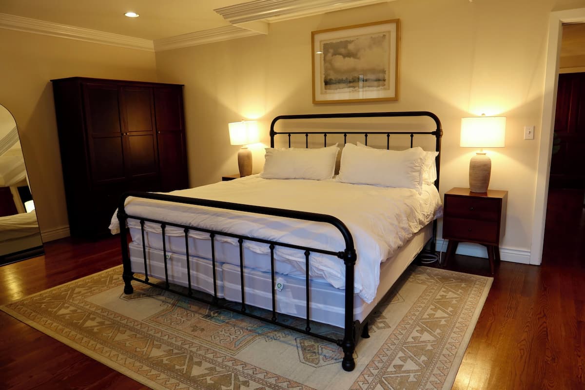 A bedroom with a bed, bedside lamps, a wardrobe, and a rug.