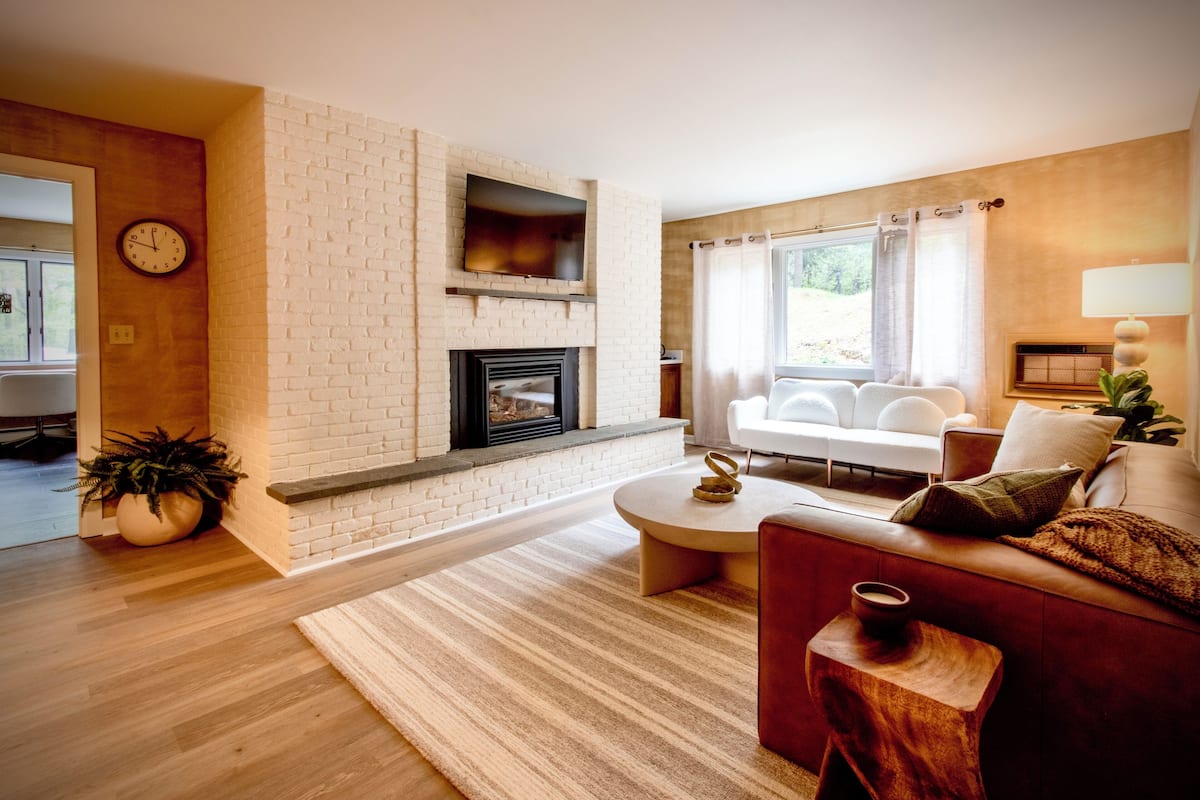 A living room with a fireplace, a sofa, a coffee table, and a TV mounted on the wall.