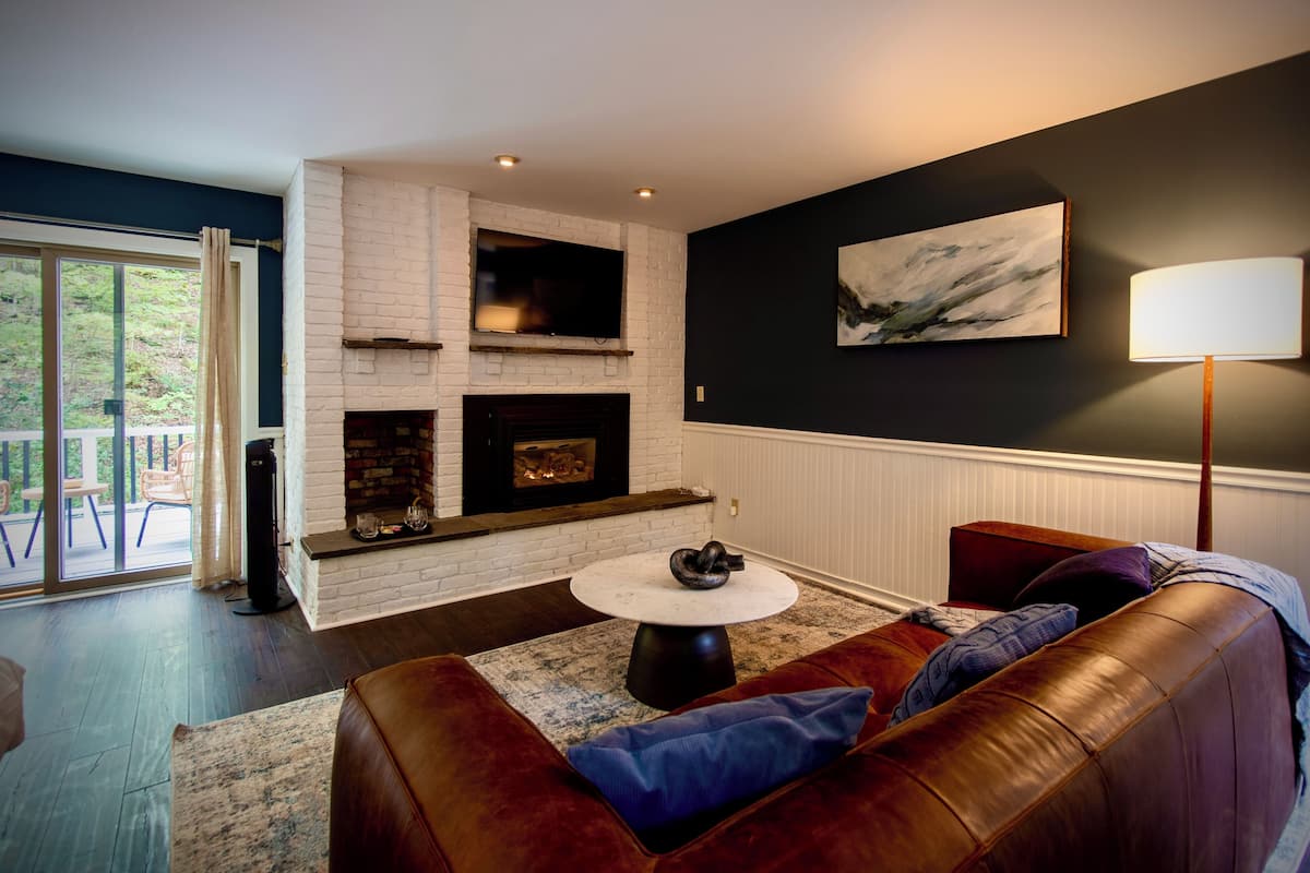 A living room with a fireplace, a couch, a round coffee table, and a painting on the wall.