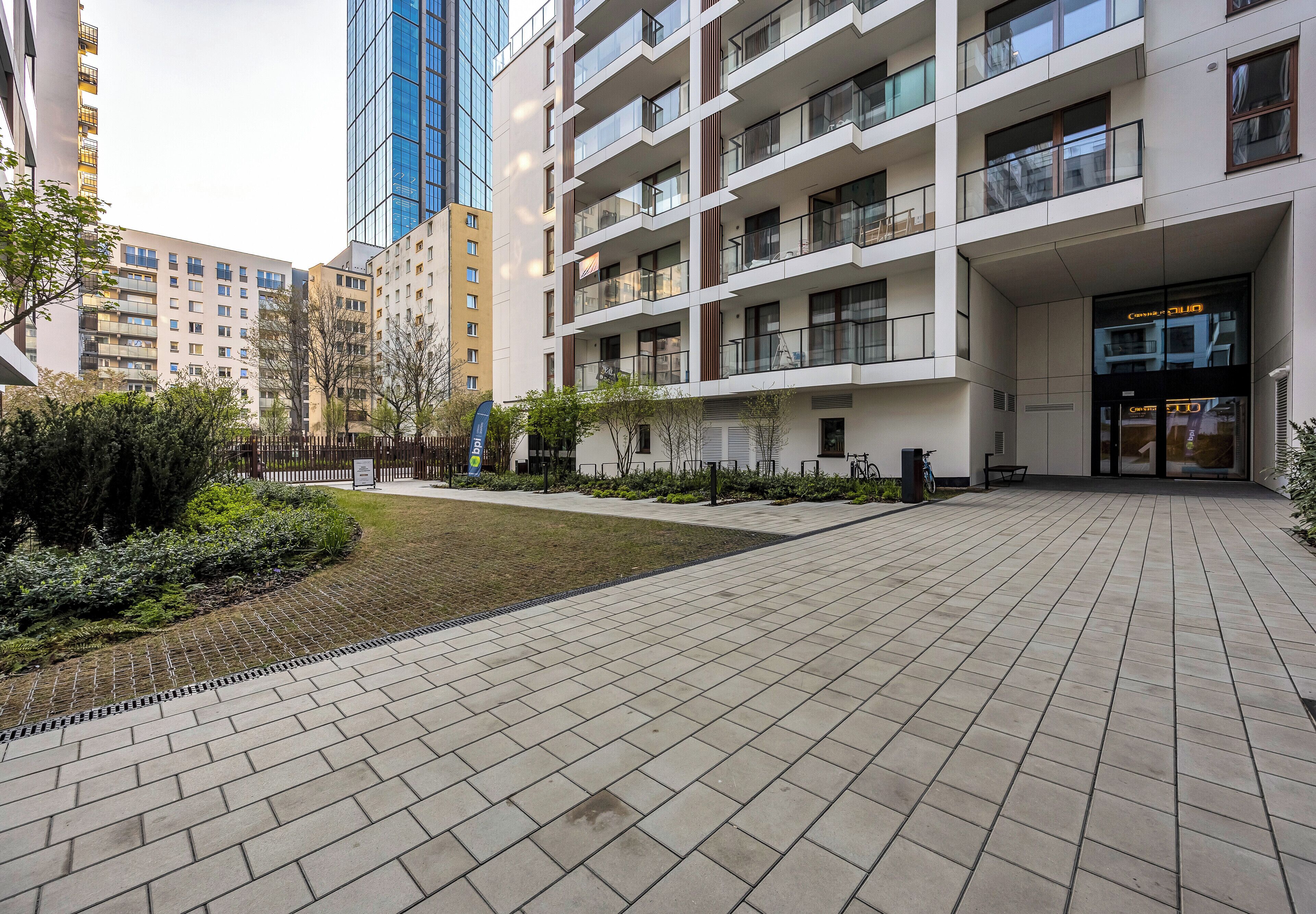 Een modern gebouw met meerdere verdiepingen, balkons en een bestraat binnenterrein.