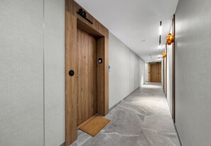 Un pasillo moderno con una puerta de madera, un felpudo y una lámpara.
