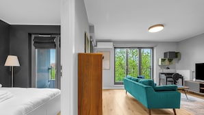 Ein modernes Schlafzimmer mit einem Bett, einem Holzschrank, einem türkisblauen Sofa und einem Schreibtisch mit Stuhl.