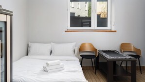 Una habitación de hotel con cama, dos sillas, una mesita y ventana con vistas.
