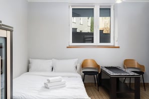 Ein Hotelzimmer mit Bett, zwei Stühlen, einem kleinen Tisch und einem Fenster mit Blick.