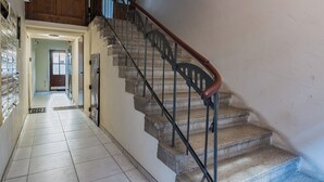 Una escalera con barandilla de madera y balaustradas de metal, que sube a un piso superior.