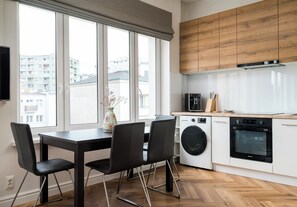 A modern kitchen with a large window, a washing machine, and a built-in oven. - Solec Powiśle Charming Apartment (Warszawa)