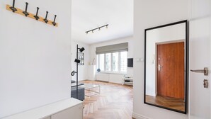 A modern interior with a wooden floor, a white wall-mounted coat rack, a large mirror, and a door with a black frame. - Solec Powiśle Charming Apartment (Warszawa)