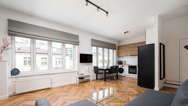 A modern apartment with a dining area, kitchen, and living room with a sofa and a glass coffee table. - Solec Powiśle Charming Apartment (Warszawa)