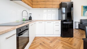 A modern kitchen with white cabinetry, a black refrigerator, and a herringbone wood floor. - Solec Powiśle Charming Apartment (Warszawa)