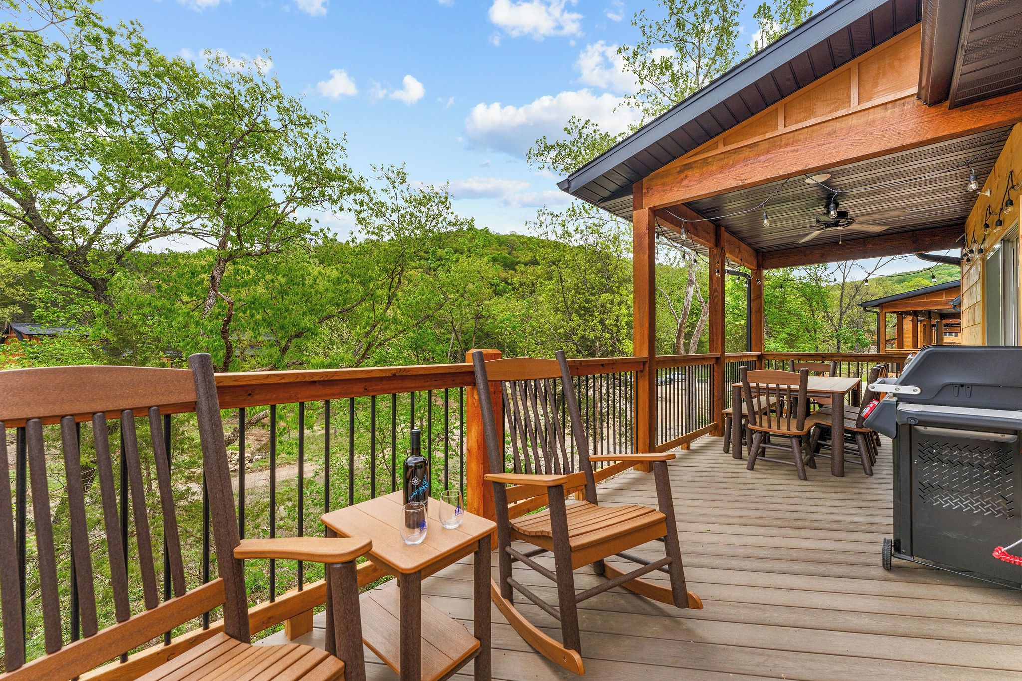 A wooden deck with outdoor seating, a barbecue grill, and a covered area with string lights.