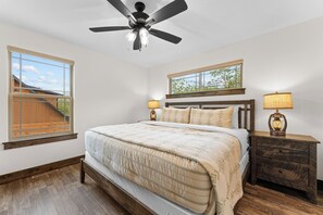 Una camera da letto con un letto, due comodini con lampade, una ventola a soffitto e una finestra vista un pontile in legno.