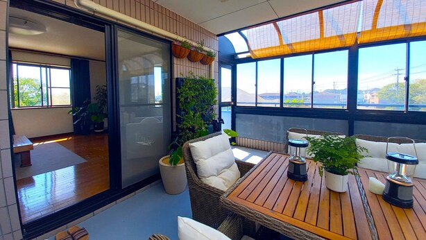 Ein modernes Interieur mit einer Schiebetür zu einem Balkon, Korbmöbeln und Blumentöpfen.