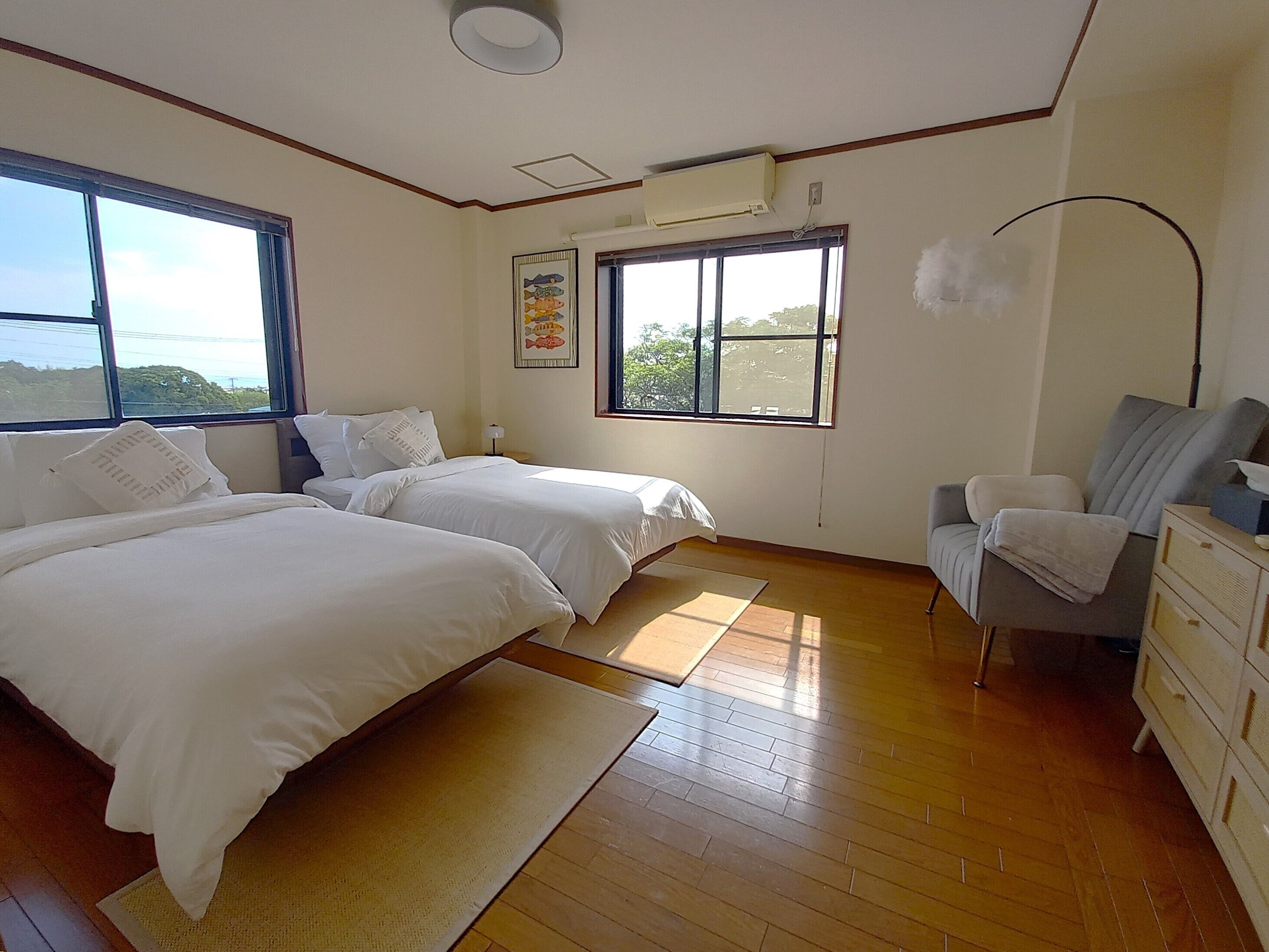 Une chambre avec deux lits, un bureau, une chaise et une fenêtre donnant sur un beau paysage.