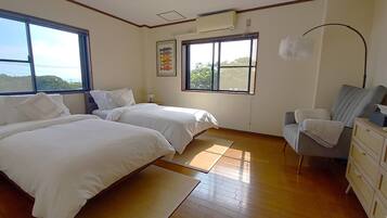 Une chambre avec deux lits, un bureau, une chaise et une fenêtre donnant sur un beau paysage.
