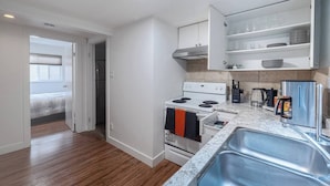 A modern kitchen with a built-in oven, a stainless steel sink, and a countertop with a coffee maker and kettle.