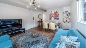 A modern living room with a sofa, coffee table, and a dining area with chairs and a table.