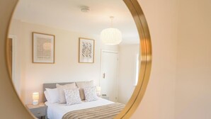 A bedroom with a bed, bedside tables, a hanging light fixture, and framed artwork on the wall. - 105 Saxmundham Road, Aldeburgh (Aldeburgh)