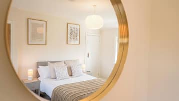 A bedroom with a bed, bedside tables, a hanging light fixture, and framed artwork on the wall.