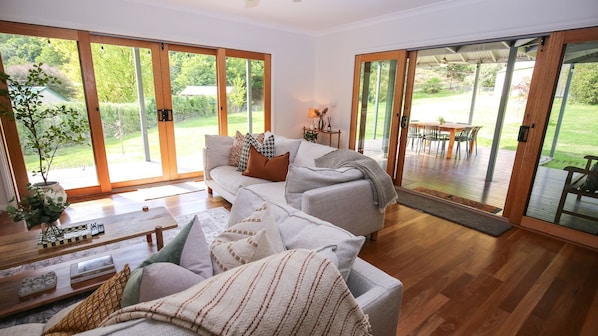 Una sala de estar con sofá, mesa de centro y vistas al exterior a través de grandes puertas corredizas de vidrio.
