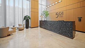 Un comptoir d’accueil avec une plaque portant le numéro « 501 », une plante en pot et un espace détente avec des chaises et une petite table.