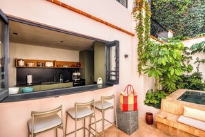 Une cuisine moderne dotée d’une grande fenêtre, de tabourets de bar et d’un coin salon avec un canapé et une petite table.