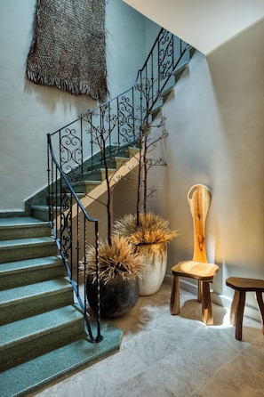 Un escalier avec une rampe en métal, une chaise en bois et deux plantes en pot.