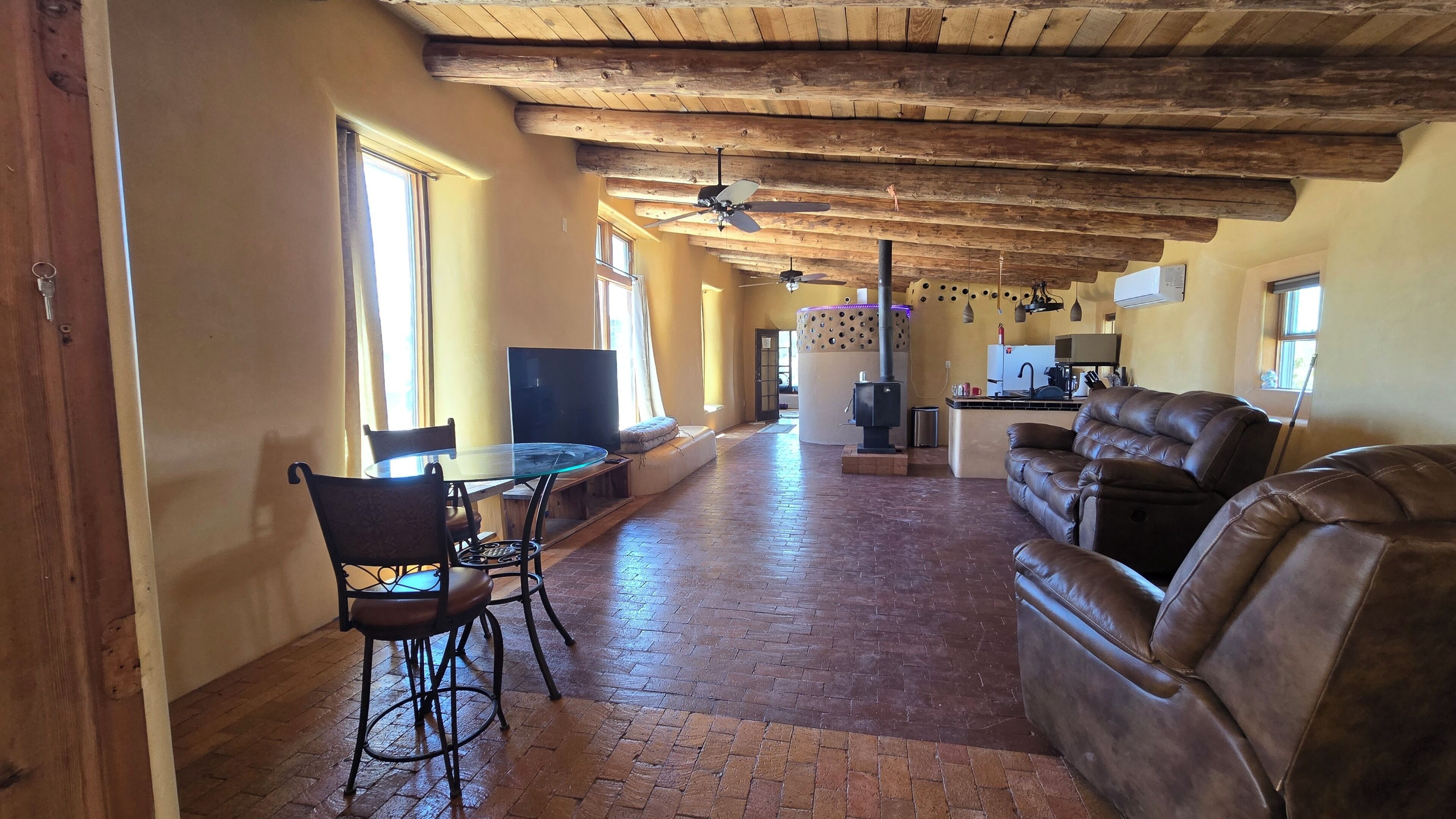 A spacious living area with a fireplace, leather sofa, and a dining table with chairs.