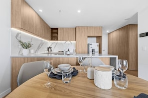 A modern kitchen with a built-in island, white marble backsplash, and wooden cabinetry. - Luxury High-Rise Stay with Panoramic GC Views (Broadbeach)