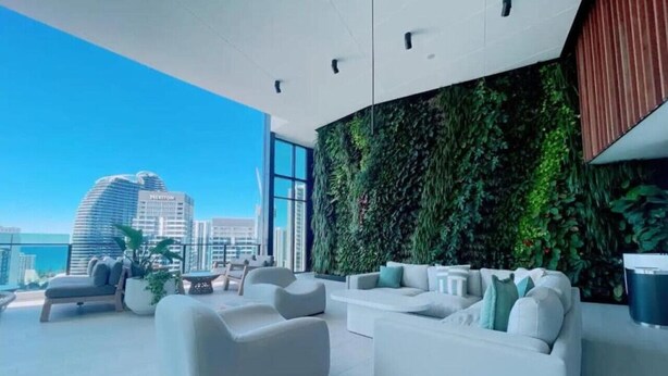 A modern living room with a large window, a green wall, and a view of a city skyline. - Luxury High-Rise Stay with Panoramic GC Views (Broadbeach)