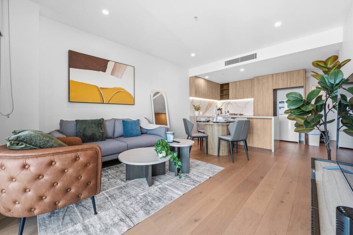A modern living room with a sofa, coffee table, and a dining area with chairs.