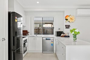 Eine moderne Küche mit Kühlschrank, Backofen, Geschirrspüler und einem Fenster mit Ausblick.