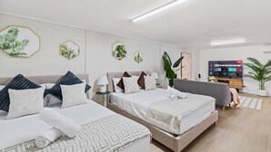 A modern hotel room with two beds, a TV, and a large plant.