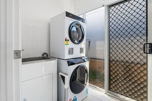 Un área de lavandería con lavadoras apiladas y un lavabo.