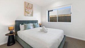 Slaapkamer met een bed, twee nachtkastjes, een plafondventilator, een raam met uitzicht en een schilderij aan de muur.