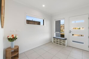 Ein heller, moderner Korridor mit einer Bank, einer Tür mit Glasfeldern und einem Fenster.