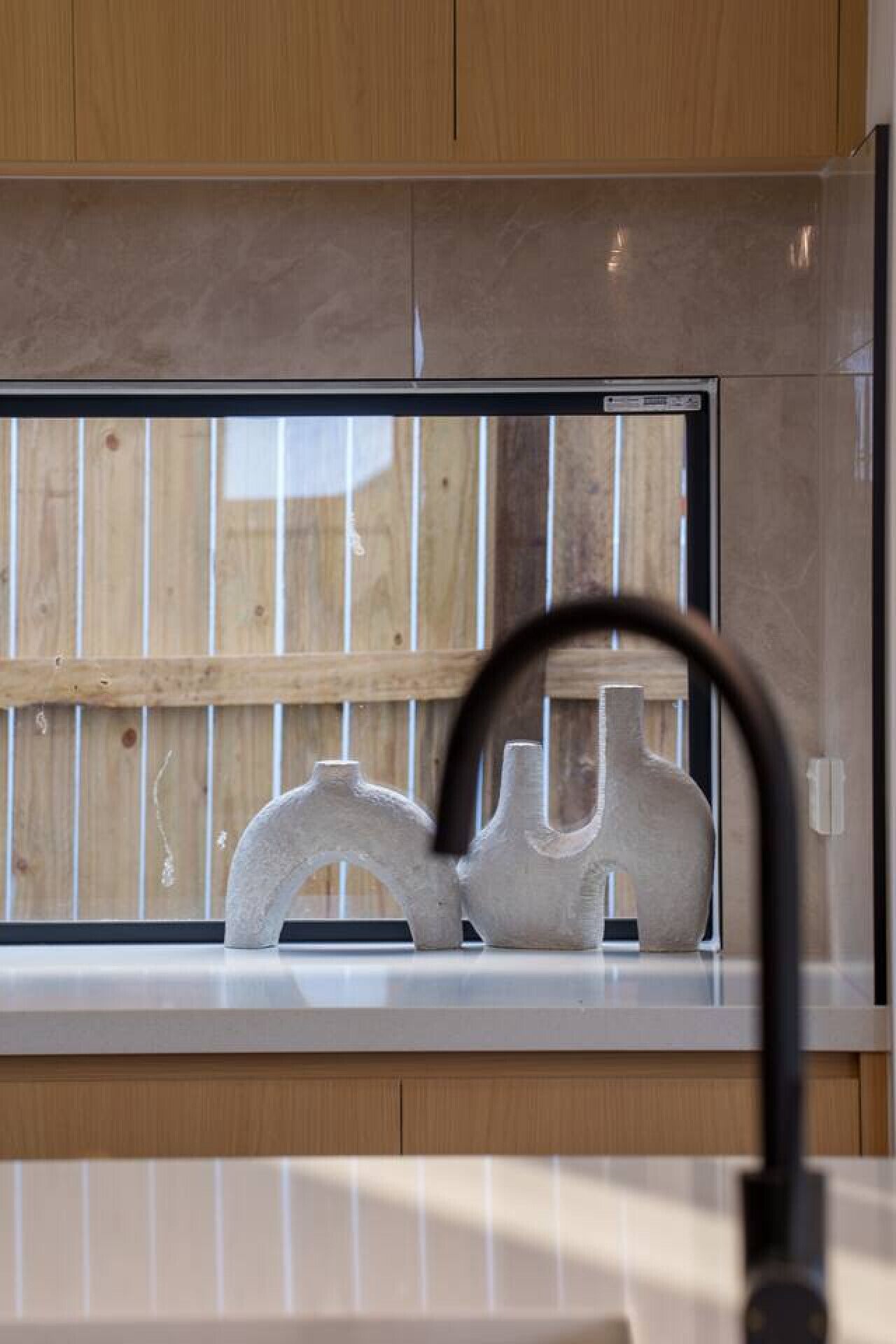 Eine Küche mit Holzausstattung, einer Edelstahl-Dunstabzugshaube und einem Fenster mit Jalousie.