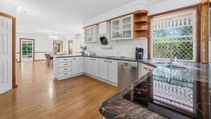 Una cocina moderna con armarios blancos, lavavajillas y encimera de granito.