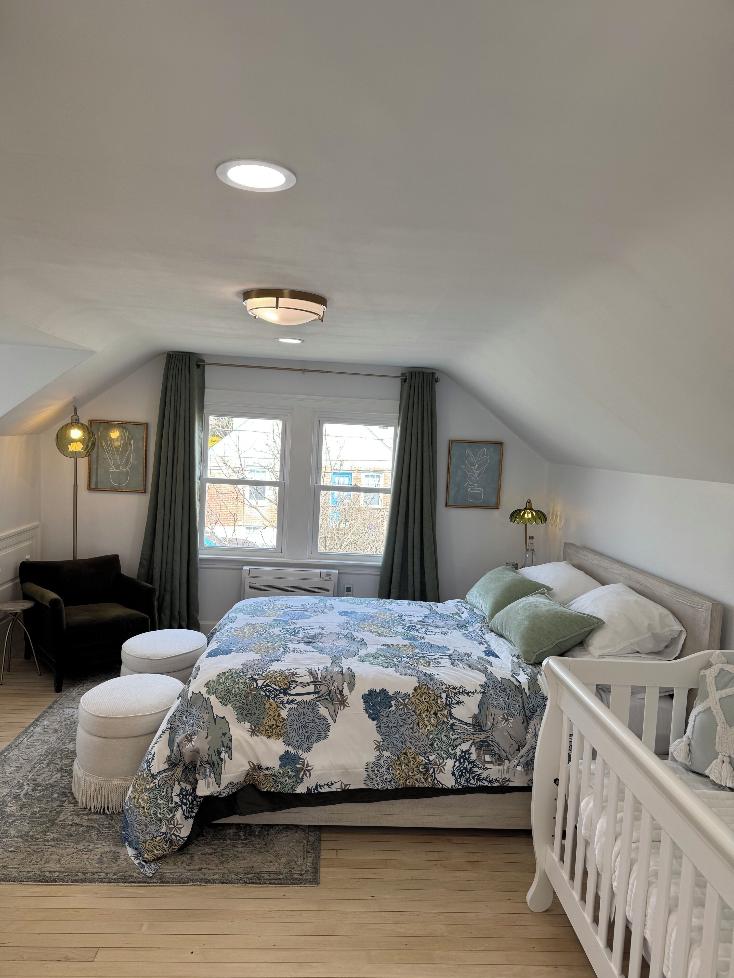 Une chambre à coucher avec un lit, un berceau, une chaise et une fenêtre.
