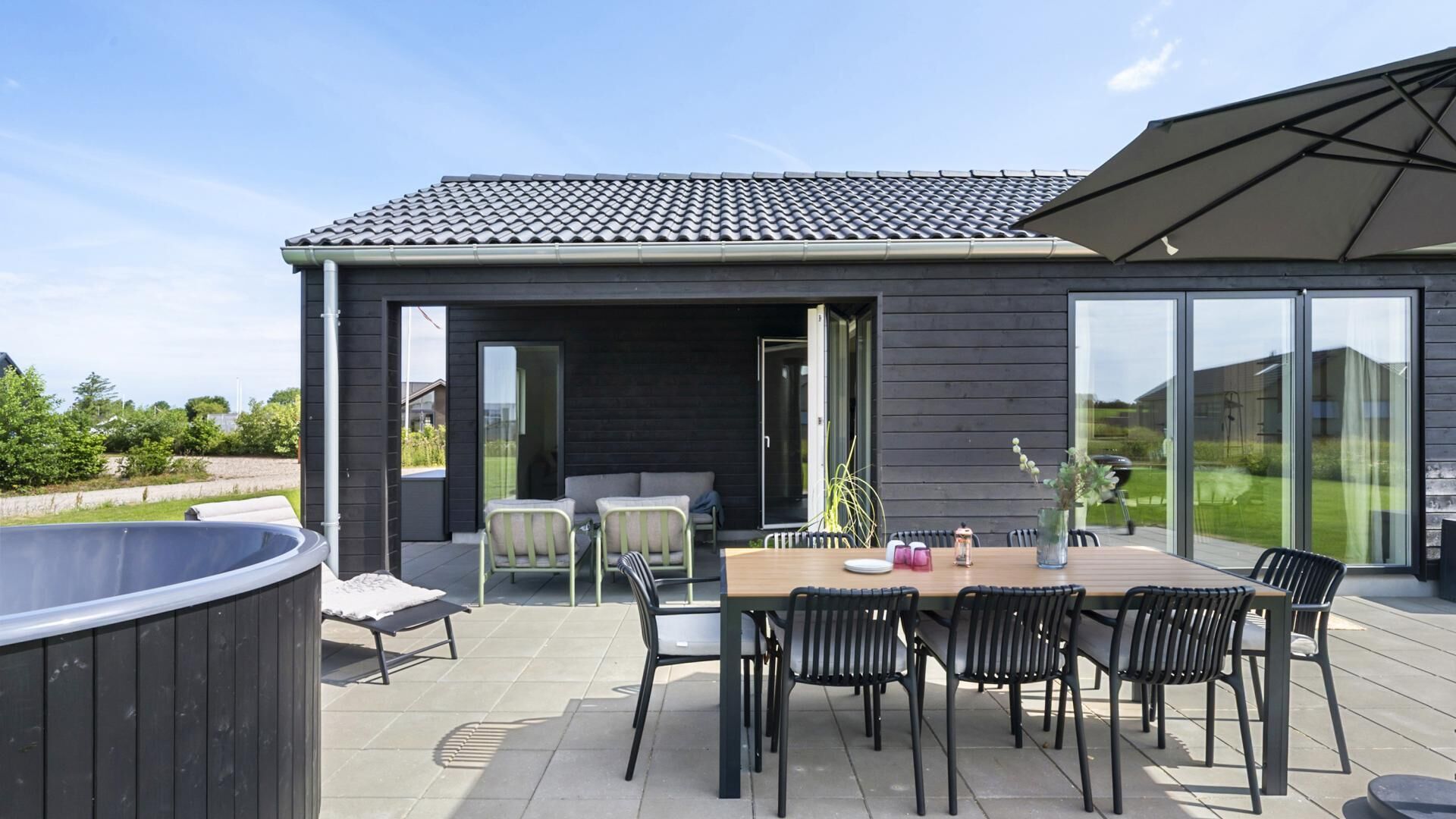 Un patio exterior con mesa y sillas, un jacuzzi y un área cubierta con vistas al paisaje.