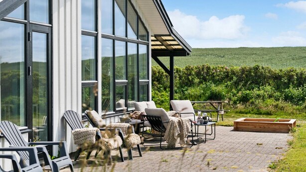 A patio with outdoor seating, a table with a coffee pot, and a view of a vineyard. - VillaVilla 954 - Fjaltring-Trans, Vestjylland (Lemvig)