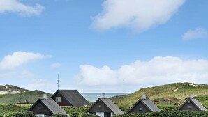A row of traditional wooden houses with pitched roofs, set against a coastal backdrop with a clear sky. - VillaVilla 954 - Fjaltring-Trans, Vestjylland (Lemvig)