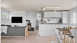 A modern interior with a living area, kitchen, and dining space, featuring a fireplace, white cabinetry, and a flat-screen TV. - VillaVilla 954 - Fjaltring-Trans, Vestjylland (Lemvig)
