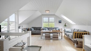 A spacious loft with a high ceiling, a dining area, and a cozy seating arrangement. - VillaVilla 953 - Fjaltring-Trans, Vestjylland (Lemvig)