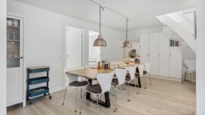 A modern kitchen with a wooden table, white chairs, and pendant lights. - VillaVilla 953 - Fjaltring-Trans, Vestjylland (Lemvig)