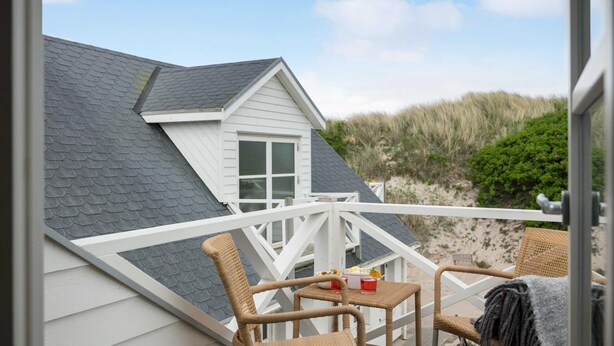 A beach house with a balcony, wicker chairs, and a table with a drink. - VillaVilla 953 - Fjaltring-Trans, Vestjylland (Lemvig)
