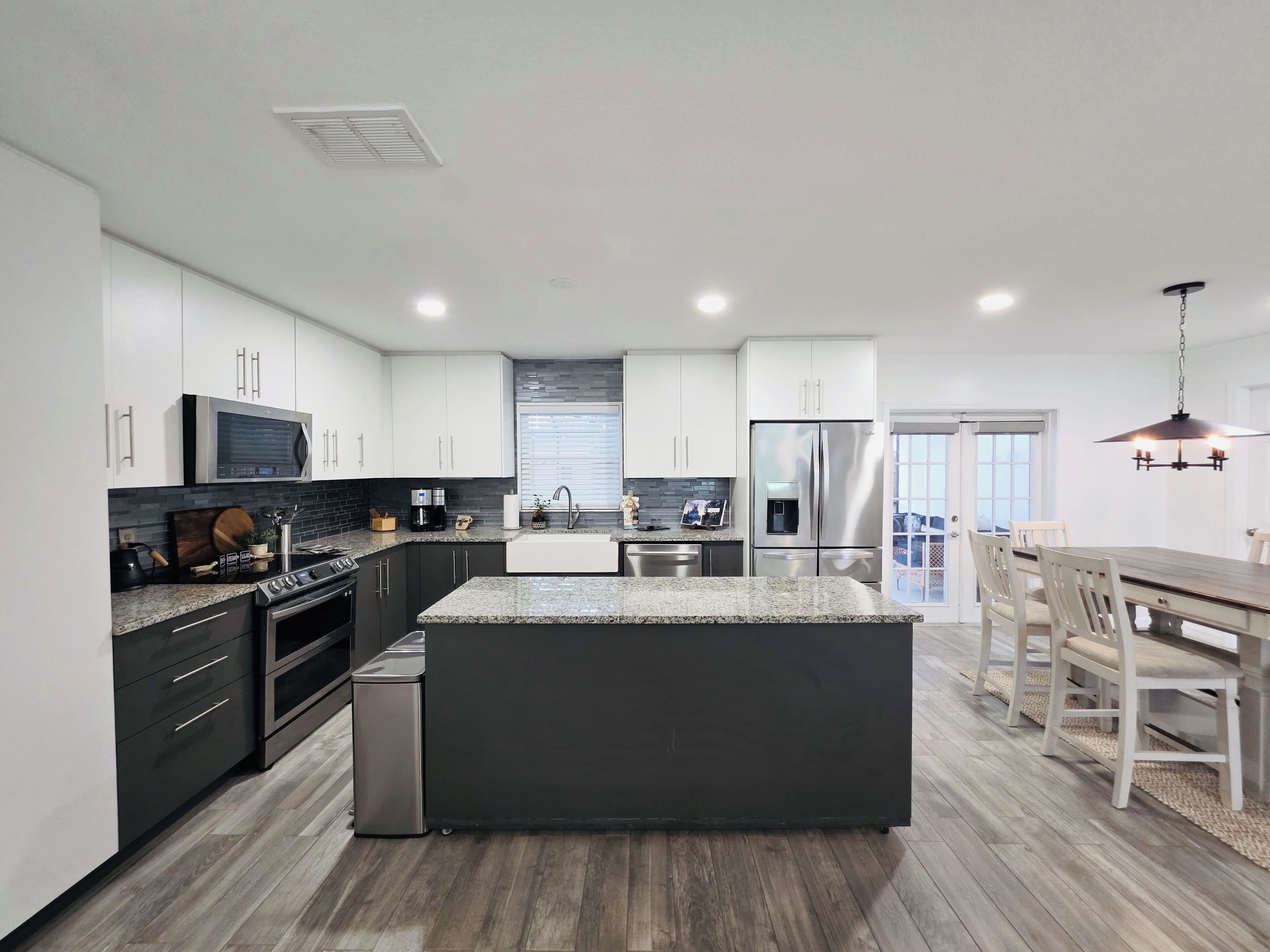 A modern kitchen with white cabinets, stainless steel appliances, and a large island.
