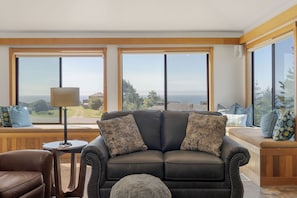 Ein modernes Wohnzimmer mit einer Ledersofa, einem runden Tisch und großen Fenstern mit Blick auf die Landschaft.