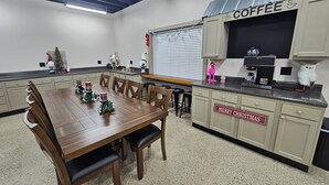 Une cuisine équipée d’un coin café, d’une table à manger avec des chaises et d’une pancarte sur laquelle on peut lire : « Joyeux Noël ».